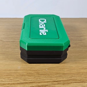 May include: A green and black plastic storage box with the word "Charlie" printed on the top.