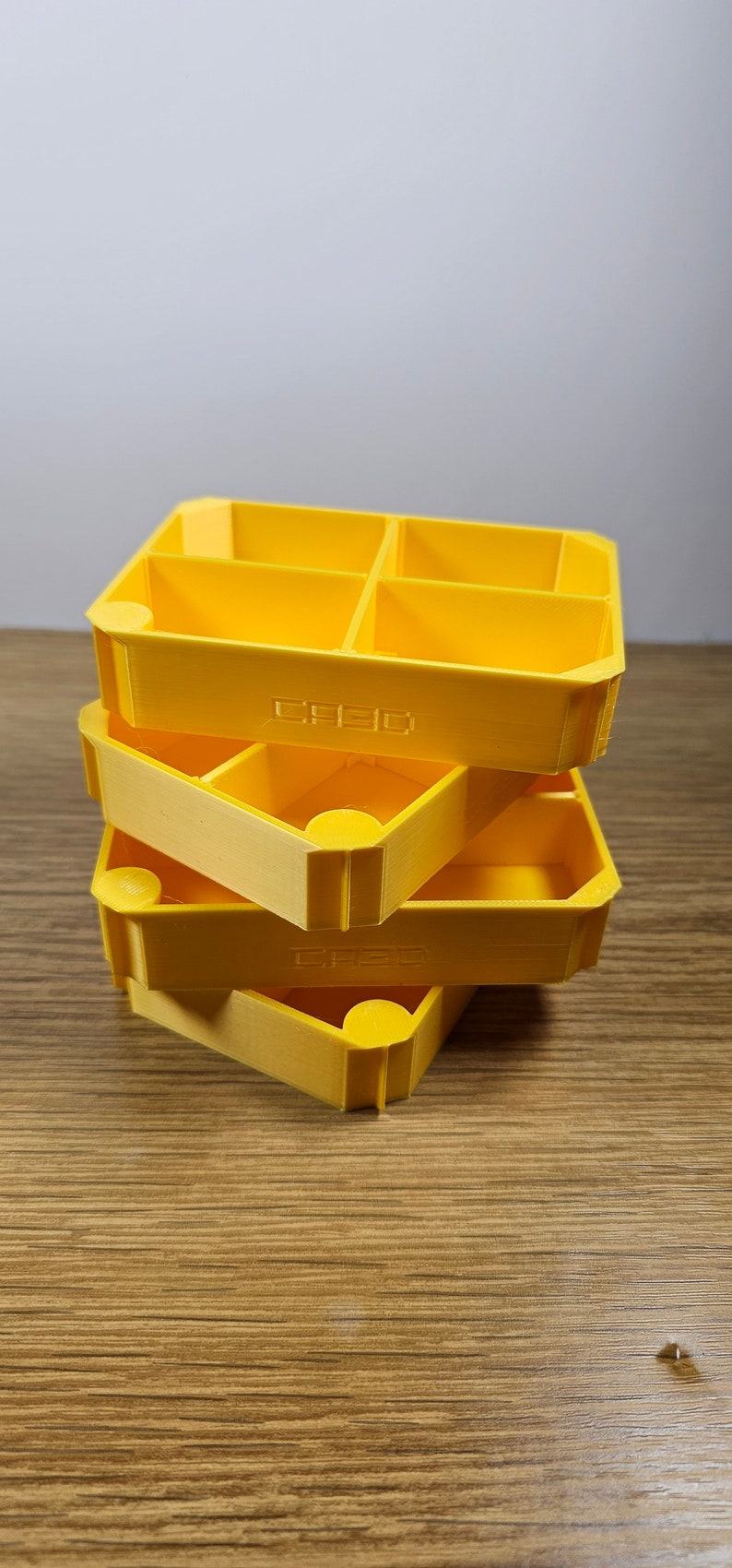 May include: Three stacked yellow plastic storage containers with multiple compartments. The containers are labelled "CREDO".