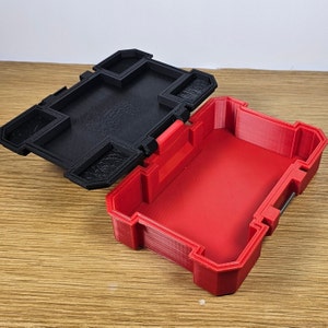 May include: A red plastic storage box with a black lid. The lid has a latch and several compartments. The box is open and empty.