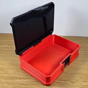 May include: A red plastic storage box with a black lid. The lid is open and the box is empty.