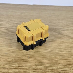 May include: A small yellow and black plastic storage box with the word "BOXX" printed on the top.