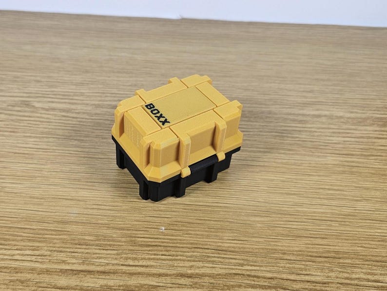 May include: A small yellow and black plastic storage box with the word "BOXX" printed on the top.