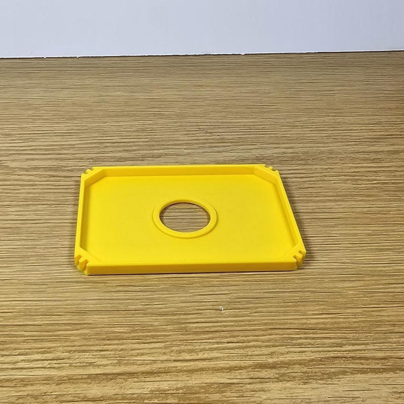 Pode incluir: Uma bandeja de pl&aacute;stico amarela com um recorte circular no centro. A bandeja tem uma borda ligeiramente elevada em torno do per&iacute;metro.