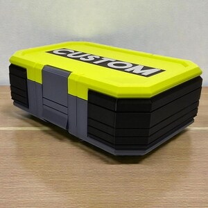 May include: A rectangular storage box with a bright yellow lid and black body. The lid features the word "CUSTOM" in white block letters. The box has gray accents and is designed for organization and storage.
