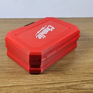 May include: A red, rectangular tool box with the word "DeWalt" printed in white on the top. The box is closed and has a black latch.