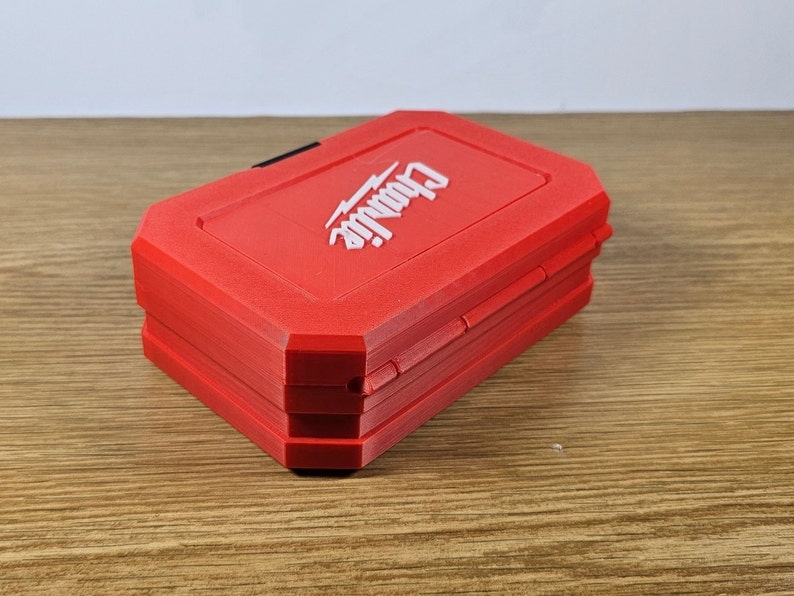 May include: A red, rectangular tool box with the word "DeWalt" printed in white on the top. The box is closed and has a black latch.