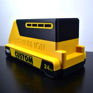 Puede incluir: Un paquete de bater&iacute;as de iones de litio amarillo y negro personalizado. El paquete de bater&iacute;as tiene el texto "LITHIUM ION", "CUSTOM", "18V" y "24AH" impreso. El paquete de bater&iacute;as est&aacute; dise&ntilde;ado para herramientas el&eacute;ctricas.