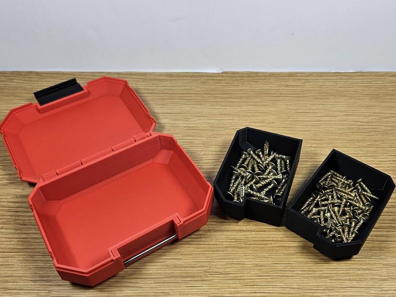 May include: A red plastic storage box with two black plastic containers filled with gold screws. The storage box is open and the containers are closed.