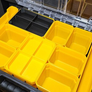 May include: A black plastic toolbox with a clear lid, containing multiple yellow plastic storage compartments of various sizes.