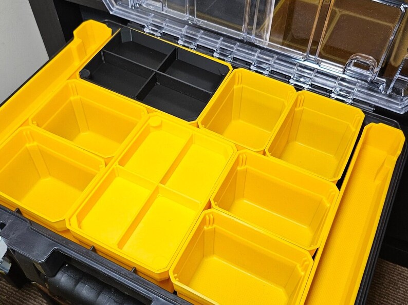May include: A black plastic toolbox with a clear lid, containing multiple yellow plastic storage compartments of various sizes.