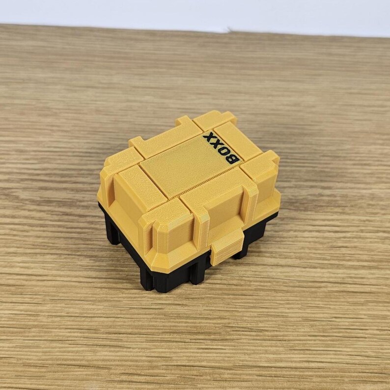 May include: A small yellow box with black trim and the word "BOX" printed on the top.