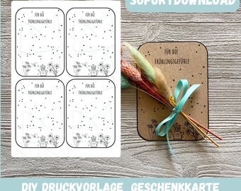 May include: Four printable cards with a black and white design featuring a watering can, flowers, and the text "FÜR DIE FRÜHLINGSGEFÜHLE". The cards are on a wooden surface with a bouquet of dried flowers and a brown card with the text "SOFORTDOWNLOAD" in the background.