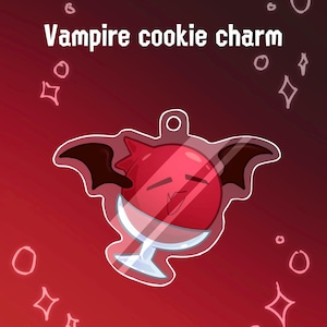 Op de afbeelding: Een rode vampierkoekjesbedel met zwarte vleermuisvleugels en een wit stengelglasontwerp. De bedel heeft de tekst "Vampire cookie charm" in het wit. De achtergrond is een verloop van rood en donkerrood met witte ster- en cirkelaccenten.