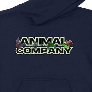 May include: A navy blue hooded sweatshirt with a kangaroo pocket. The front features the text "ANIMAL COMPANY" in a colorful, stylized font with animal illustrations. The hood is up, and the sweatshirt is displayed on a white background.