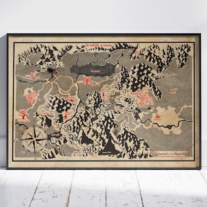 May include: Framed fantasy map print featuring a detailed, illustrated landscape with mountains, a lake, and various locations labeled in red. A compass rose is in the lower left corner. The map is in shades of gray and brown.