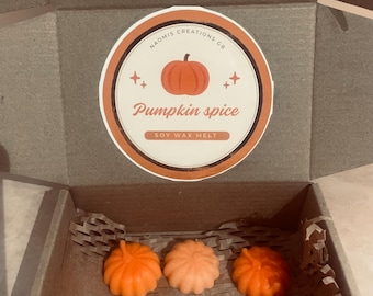 May include: A cardboard box with six pumpkin-shaped soy wax melts in shades of orange and peach. The box has a circular sticker with a pumpkin illustration and the text "Pumpkin spice soy wax melt."