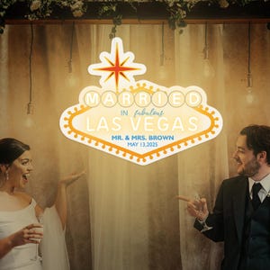 K&ouml;nnte beinhalten: Ein Schild im Stil des Las Vegas-Willkommensschildes mit den Worten "MARRIED in fabulous LAS VEGAS" in einer Retro-Schriftart. Das Schild enth&auml;lt auch die Namen "MR. & MRS. BROWN" und das Datum "MAY 13,2025".