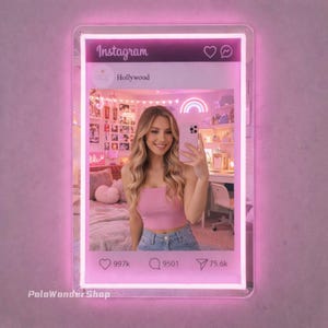 May include: A pink neon-lit Instagram-themed wall decor piece. The image within the frame shows a person taking a selfie in a pink-themed room. The Instagram interface includes the word "Instagram", a profile name, and like, comment, and share icons.