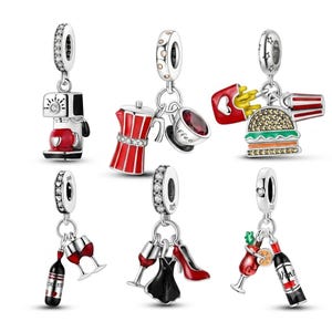 Puede incluir: Una colección de seis dijes de metal plateado con diversos diseños, incluyendo una cafetera, una cafetera italiana con taza, una hamburguesa con papas fritas, botellas de vino con copas, un vestido negro con zapato de tacón rojo y una copa.