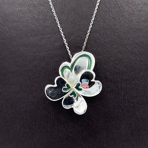 May include: Silver necklace with a green and silver four-leaf clover pendant.