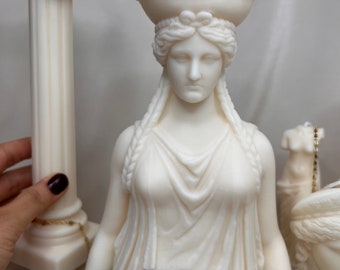 Puede incluir: Escultura de vela blanca de un busto de mujer con una corona, sobre una base de mármol. La escultura es una réplica de una estatua griega clásica.
