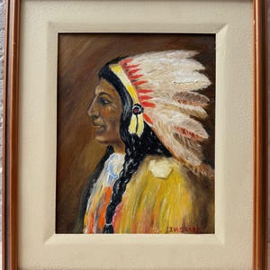 May include: An oil painting in a brown wooden frame depicting a profile view of a person wearing a feathered headdress with red and white feathers. The person has long black braided hair and wears a yellow garment. The signature J.H. SHARP is visible.