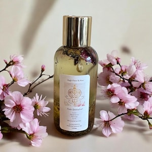 May include: A glass bottle with a gold cap filled with a clear liquid and herbs. The label reads "Magic Flame by Kate" and "Finda Spiritual oil" with the words "Love, Prosperity, Success, Luck" listed below. The bottle is 120ml and contains herbs and essential oils.