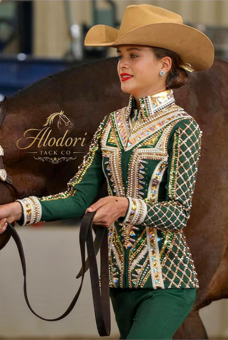 Puede incluir: Chaqueta de equitaci&oacute;n verde y dorada con intrincados abalorios y adornos. La chaqueta presenta un cuello alto y mangas largas, combinada con un sombrero de vaquero marr&oacute;n. Se ve el logo "Alodori Tack Co".