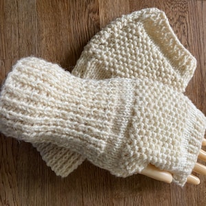 May include: A pair of cream-coloured knitted fingerless gloves with a textured stitch pattern.