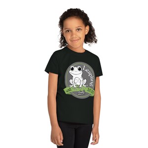 Puede incluir: Camiseta negra con un diseño de rana de dibujos animados dentro de un círculo gris, con el texto "1 Leapling 2020". La rana es blanca con ojos grandes y está sentada en una pancarta verde que dice "est. Limited Edition".