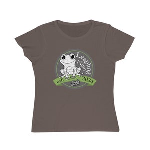 Puede incluir: Una camiseta marrón con un gráfico de rana verde y blanca. El gráfico dice "Leaping Mom est. 2024 Limited Edition".