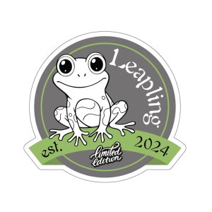 Puede incluir: Una pegatina circular gris y verde con una rana de dibujos animados, el texto "Leaplings est. 2024", y las palabras "edición limitada" en cursiva.