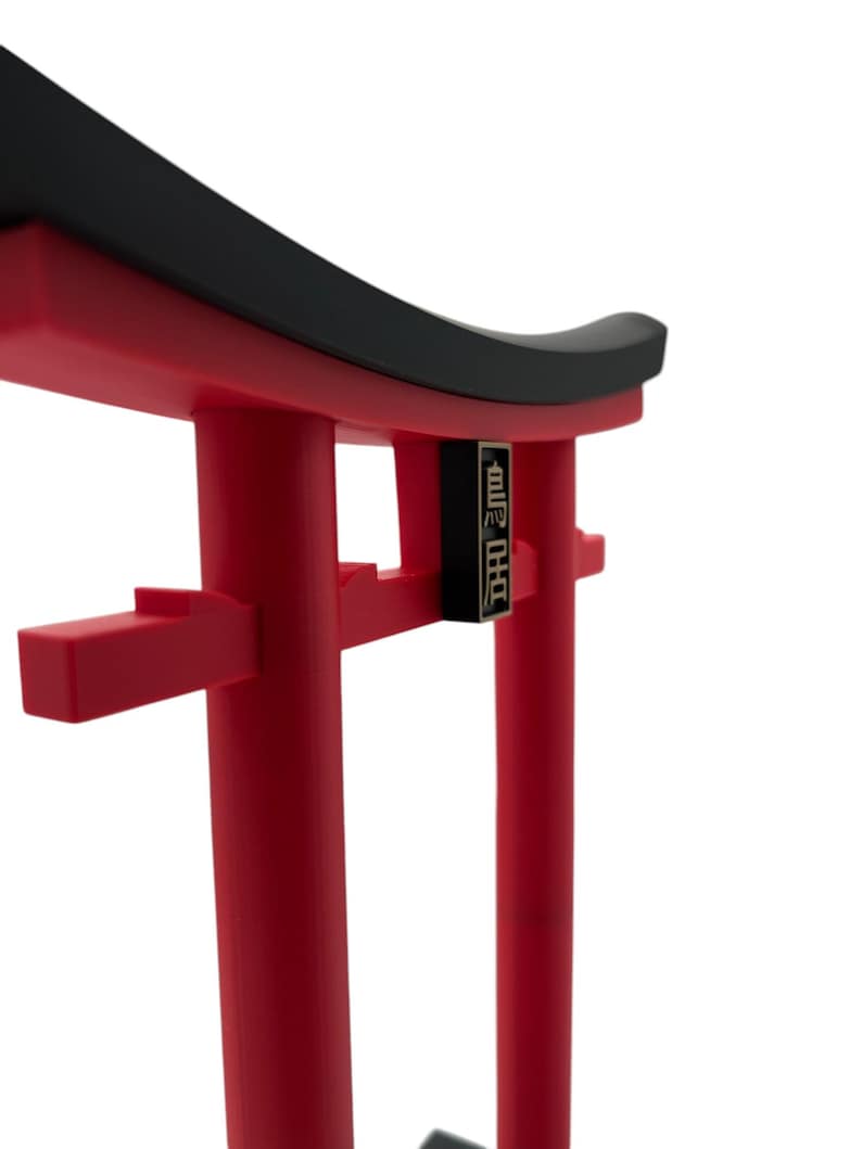 May include: A red and black torii gate, a traditional Japanese gateway, with the Japanese characters "御神門" written on the front.