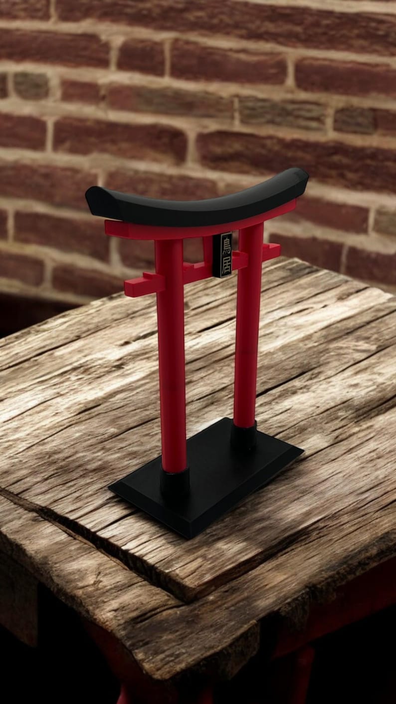 May include: A red and black miniature torii gate, a traditional Japanese gateway, with the text "MINI TORII" on the top beam. The gate is sitting on a wooden surface.