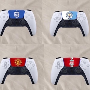 May include: Four white and black wireless game controllers featuring custom centre panels. The top left displays the England national team crest, the top right shows the Manchester City logo, the bottom left features the Manchester United crest, and the bottom right displays the Liverpool Football Club emblem.