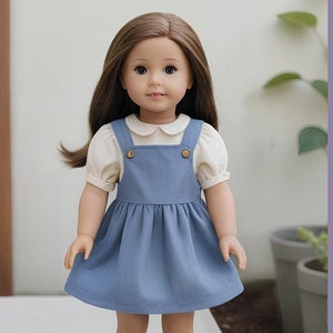 May include: A doll wearing a blue overall dress with a white blouse and a white collar. The doll has brown hair and blue eyes. The text "BERRY BASIC" is visible in the background.