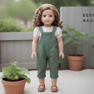 May include: A doll wearing a green overall dress with a floral print blouse and brown shoes. The doll has long brown hair and blue eyes. The doll is standing in front of a white fence with the words "Berry Basic" written on it.