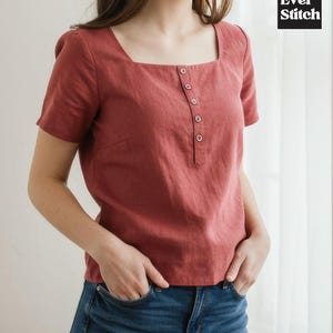 May include: A short-sleeved, brick-red linen top with a square neckline and a button-up placket. The top is paired with blue jeans. The Ever Stitch logo is in the upper right corner.