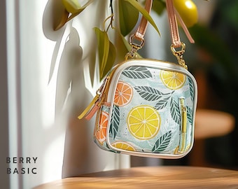 May include: A small, square, light blue and green patterned handbag with a gold zipper and a gold chain strap. The bag features a lemon and leaf design.