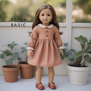 May include: A doll wearing a peach-colored dress with a white lace collar and cuffs. The doll has brown hair and blue eyes. The doll is standing on a white surface with two potted plants in the background. The text "BERRY BASIC" is visible in the background.