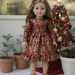 May include: A doll wearing a burgundy dress with a gold floral pattern, matching hair bow, and brown shoes. The text "BERRY BASIC" is in the upper left corner. A decorated Christmas tree is in the background.