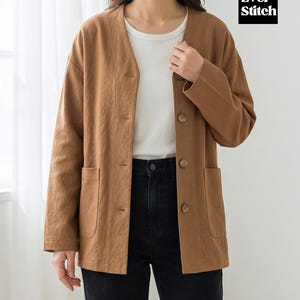 May include: A brown jacket with a V-neck, button closure, and two front pockets. The jacket is worn over a white t-shirt and paired with black jeans. The brand name "Ever Stitch" is visible in a black box.