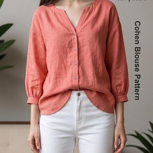 Könnte beinhalten: Eine korallenfarbene Bluse mit Dreiviertelärmeln, einem V-Ausschnitt und einer Knopfleiste vorne. Die Bluse trägt den Text berry basic und Cohen Blouse Pattern. Sie wird mit einer weißen Hose kombiniert, die einen sichtbaren Knopf am Bund hat.