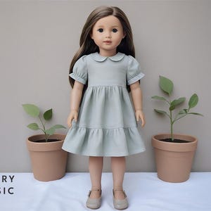 May include: A doll in a pale green dress with a Peter Pan collar and a tiered skirt. The doll has brown hair and is positioned in front of a plain backdrop. The text "BERRY BASIC" is visible at the bottom.