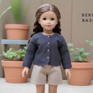 May include: A doll wearing a dark blue cardigan with a button closure and beige shorts. The doll has long brown hair and blue eyes. The text "BERRY BASIC" is visible in the upper right corner of the image.