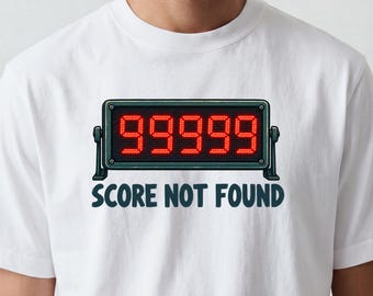 以下が含まれることがあります： 明るい赤色のLEDスタイルの数字で99999と表示された長方形のデジタルスコアボードのグラフィックが特徴の白いTシャツ。スコアボードの下には、濃い青色の太字のサンセリフフォントで「SCORE NOT FOUND」というテキストがプリントされています。
