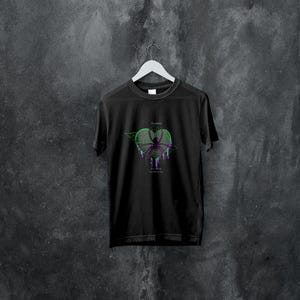 Puede incluir: Camiseta negra con un estampado gráfico de una araña en una telaraña en forma de corazón. El texto "They watch, they wait, and then they strike" está impreso debajo de la araña.