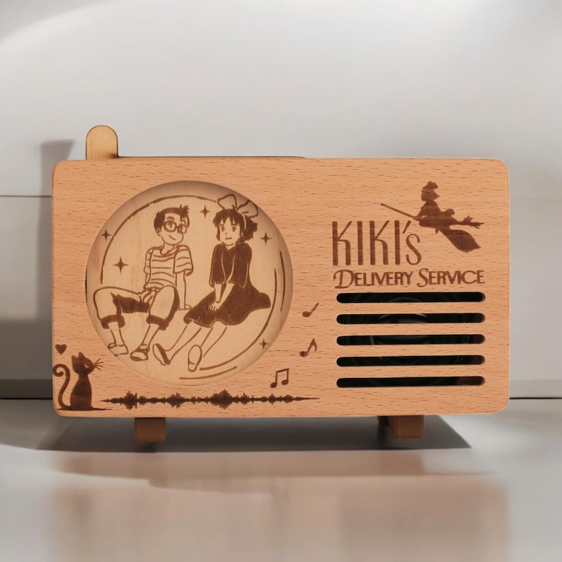 May include: A wooden music box with a laser-engraved design featuring Kiki and Tombo from the movie Kiki's Delivery Service. The music box has a speaker grill and the text "Kiki's Delivery Service".