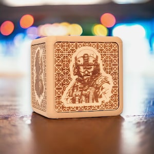May include: A wooden box with a geometric pattern and a laser-etched image of a soldier wearing a helmet and tactical gear.