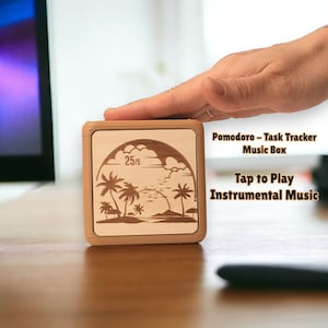 May include: A wooden box with a tropical scene engraved on the top. The box is labeled "Pomodoro - Task Tracker Music Box" and "Tap to Play Instrumental Music". The box has a timer display that reads "25/5".